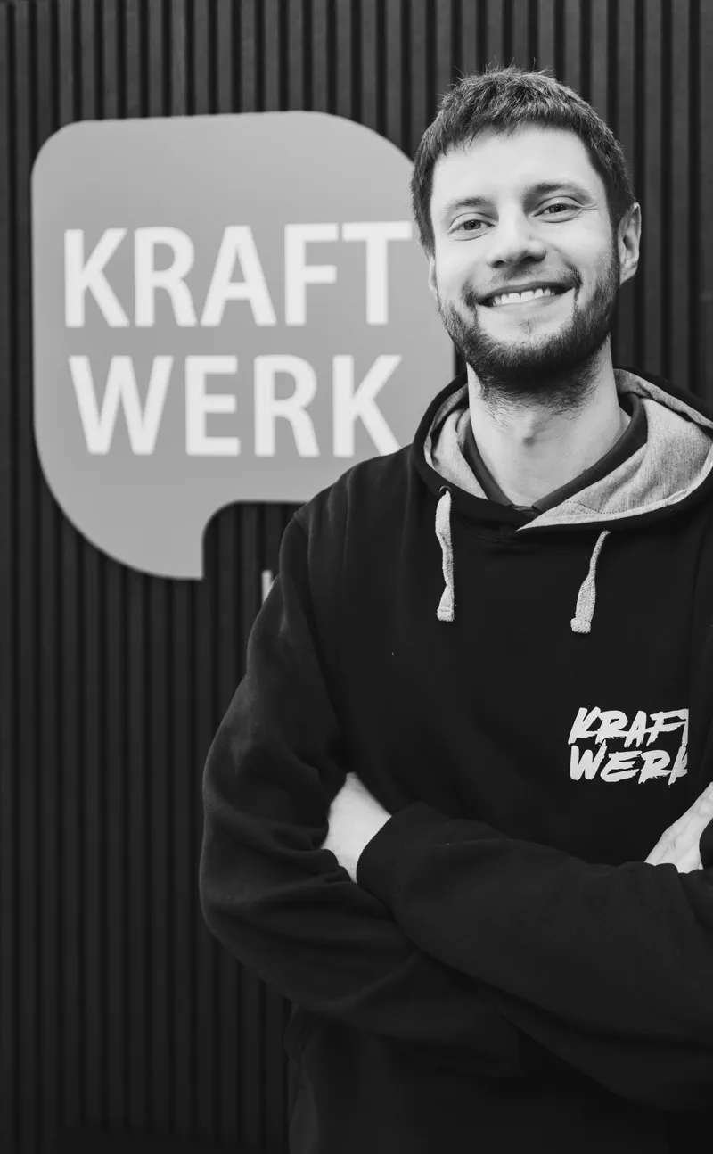 Trainer im Kraftwerk-Hoodie vor dem Wandlogo, Schwarzweiß-Porträt